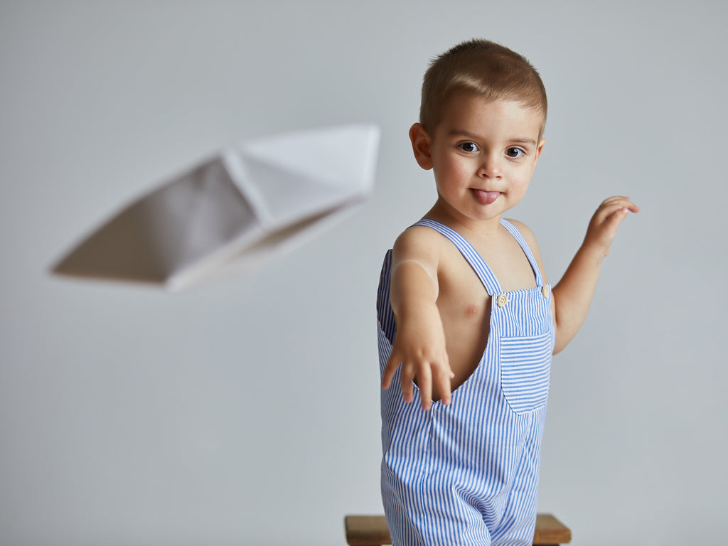 Child wearing a blue and white striped outfit with shoulder straps.